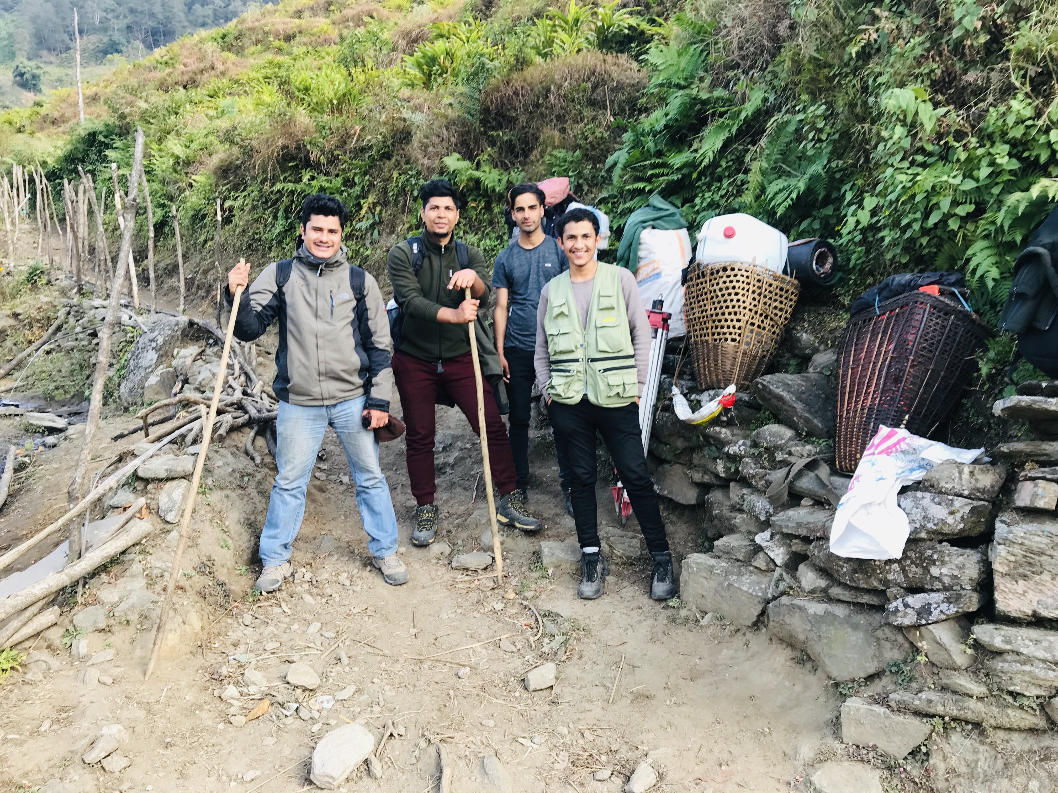 Geophysics team taking a break during an 8-day hike through Nepal's hills, carrying equipment and supplies
