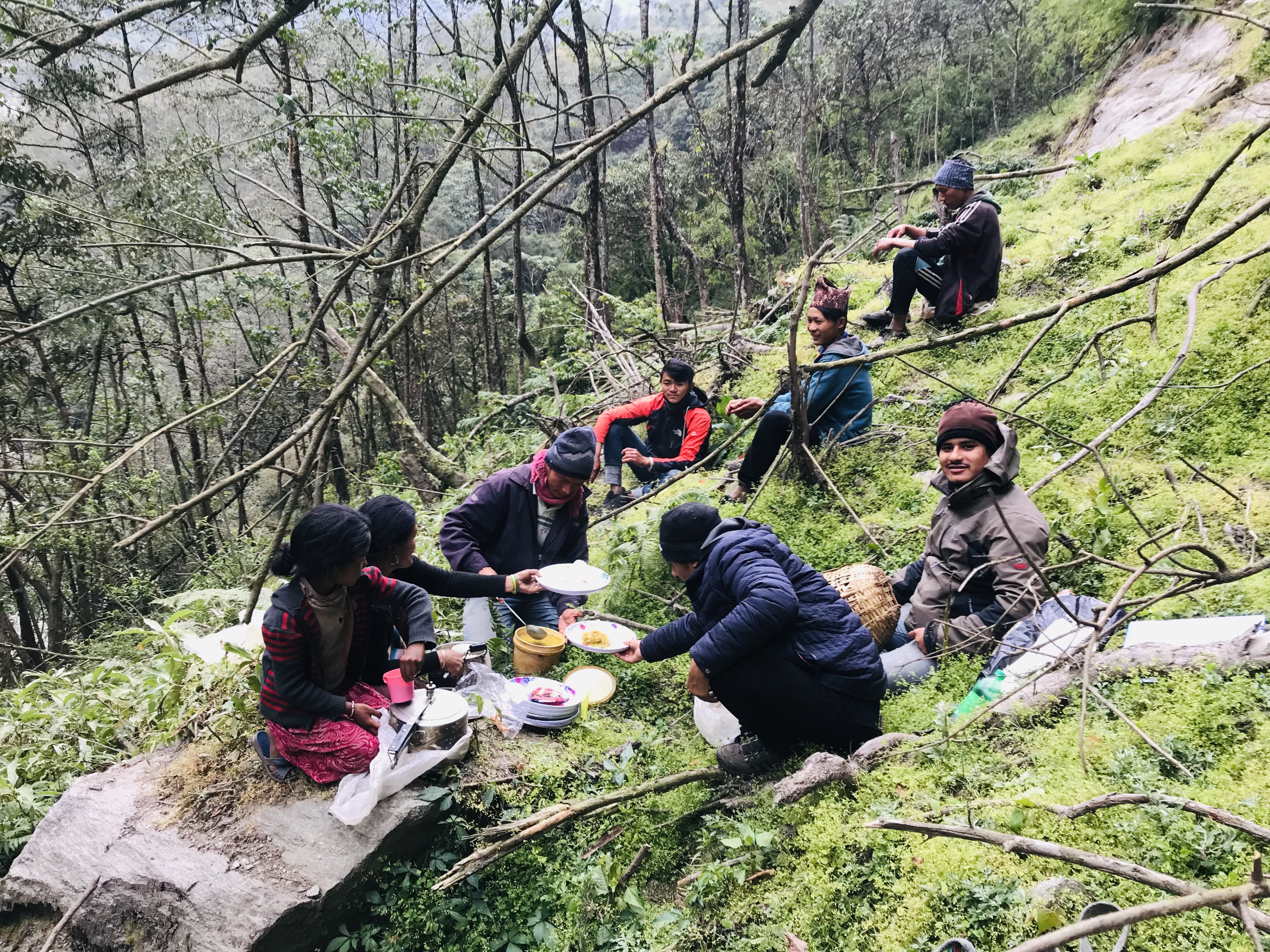 Team sharing a communal lunch at a remote project site in Nepal, including engineers, porters, and cooks